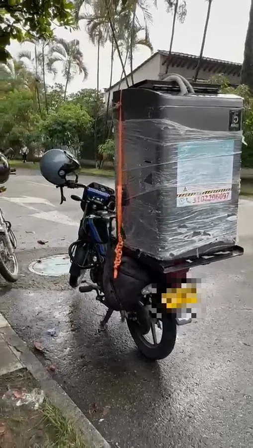 Domiciliario de Las Lavadoras llevando una lavadora protegida en la parrilla de su moto